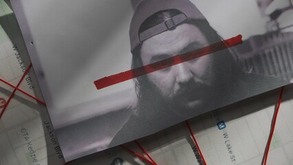 Close up shot of investigation board. Detective board shot map of crime, pinned photograph of male suspect or victim with red line on face.