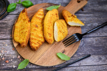 
 Crispy home made  deep fried   chicken strips . Breaded  with cornflakes chicken  breast fillets  with chilly peppers and fresh   basil on wooden rustic background