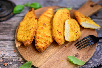 
 Crispy home made  deep fried   chicken strips . Breaded  with cornflakes chicken  breast fillets  with chilly peppers and fresh   basil on wooden rustic background