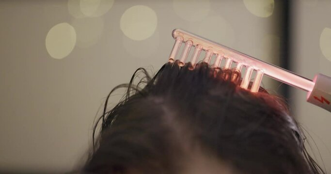 Hair Care. Woman receives a Procedure using the Darsonval device at home. Close-up of the Head. Concept of professional Cosmetology
