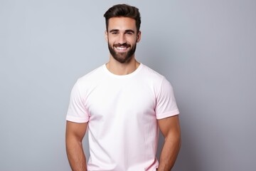 Strong man 18 years old, calm happy expression, calm happy smile, man in white t-shirt and pink pants, dark hair, beard, clean light background 