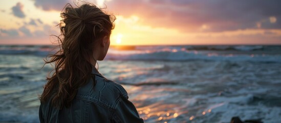 Girl gazes at ocean sunset.