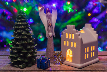Angel, building candle light, gift, snowflake and christmas tree on wood table. Decoration background