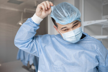 Portrait of a tired surgeon taking off his hat after hard surgery, while leaving an operating room