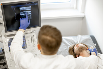 Young guy during an ultrasound diagnosis of the carotid artery. Concept of ultrasound diagnostics and men's health. Idea of examination of cardiovascular diseases - obrazy, fototapety, plakaty