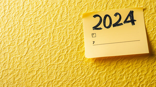 2024 date handwritten in a text script with a black marker pen on paper note pad memo placed on a yellow background for a calendar, poster or greeting card, stock illustration image