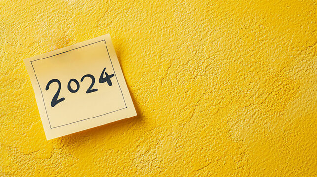 2024 date handwritten in a text script with a black marker pen on paper note pad memo placed on a yellow background for a calendar, poster or greeting card, stock illustration image