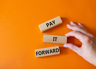 Pay it forward symbol. Concept words Pay it forward on wooden blocks. Beautiful orange background. Businessman hand. Business and Pay it forward concept. Copy space.