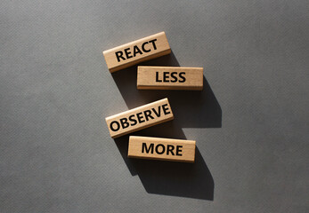 React less Observe more symbol. Wooden blocks with words React less Observe more. Beautiful grey...