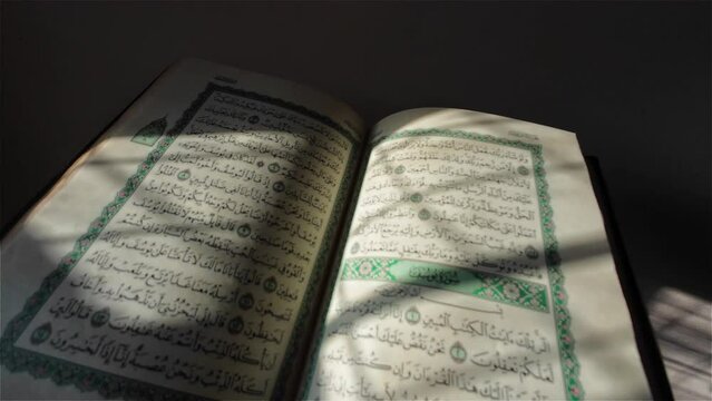 Side shot of an opened Quran, the focus moves along the opened page