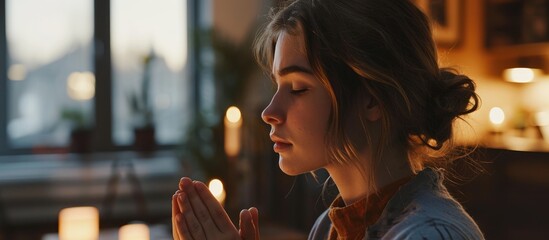 A young woman in her modern home, with Christian faith and gratitude, praying to God.
