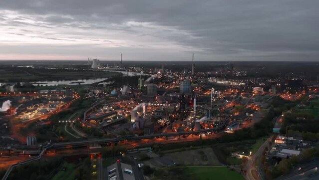 Industry of Ruhr: Aerial night skyline view of ThyssenKrupp steel production plant with industrial blast furnace in the foreground. Duisburg, Germany