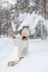 Fototapeta premium A girl throws snow up in winter.