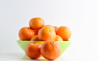Tangerines on white background and green porcelain plate. 