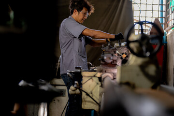 Asian worker in production plant drilling at machine. Professional worker near drilling machine on factory. finishing metal working internal steel surface on lathe grinder machine with flying sparks.