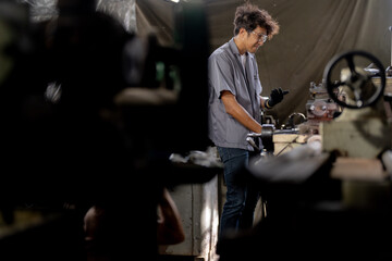 Asian worker in production plant drilling at machine. Professional worker near drilling machine on factory. finishing metal working internal steel surface on lathe grinder machine with flying sparks.