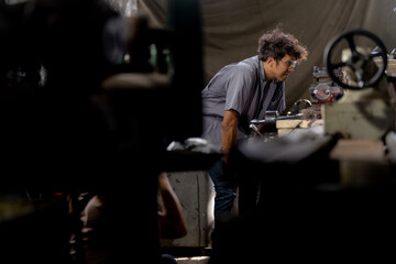 Asian worker in production plant drilling at machine. Professional worker near drilling machine on factory. finishing metal working internal steel surface on lathe grinder machine with flying sparks.