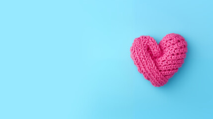 A pink knitted heart on a blue background in top view flat lay style with copy space for text. Valentine's Day, hobby, knitting, love, healthcare concept. Valentine's Day background.