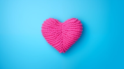 A pink knitted heart on a blue background in top view flat lay style. Valentine's Day, hobby, knitting, love, healthcare concept.