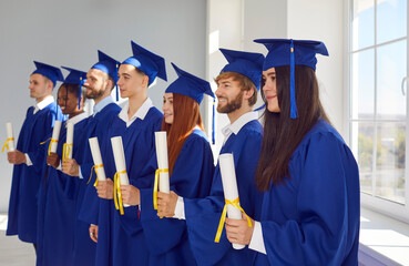 Portrait of a group of smiling happy multiracial diverse graduates students standing in a row in a...
