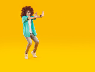 Happy boy in curly brown wig jumping in air. Full length portrait of funny joyful boy wearing...