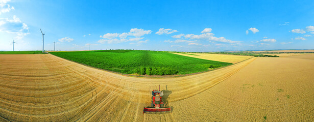 Combine in the field of wheat and 360 summer panorama with blue sky. and with wind turbines in the...
