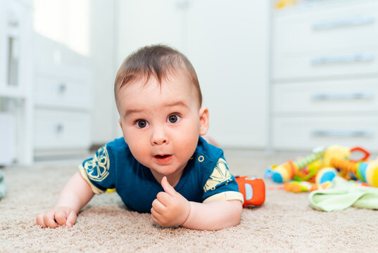 A Curious Baby Exploring a Colorful Toy Collection. A baby laying on the floor with toys