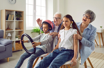Happy grandparents and children spend free time together, play games and have fun. Funny grandma,...