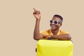 Happy handsome African American tourist man in cool stylish sun glasses smiles and points his index...