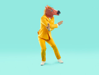 Full length shot of dancing young man in horse head mask. Eccentric man wearing horse latex mask...