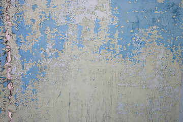 Peeling paint on the wall. Old concrete wall with cracked flaking paint. Weathered rough painted surface with patterns of cracks and peeling. Grunge texture for background and design. High resolution.