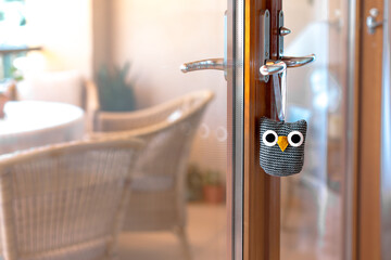 A cute owl doorstopper hangs on the handle of a wooden door, blending practicality with charming home decor.