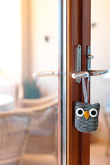 A cute owl doorstopper hangs on the handle of a wooden door, blending practicality with charming home decor.