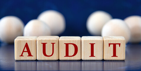 AUDIT - word on wooden cubes on a blue background with wooden balls