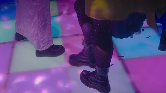 People are dancing disco on a disco field glowing with colorful squares. Vintage disco with dancing girls and men. A party at a nightclub in the style of the 80s. Modern flashing floor in a nightclub