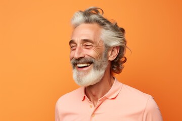 Obraz premium Portrait of happy senior man with grey hair and beard, isolated on orange background