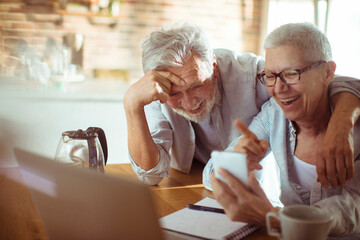 Joyful Senior Couple Sharing a Laugh Over a Smartphone at Home