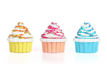 Isolated cupcakes in a row. Fake small cupcakes miniatures made with pearls and glitter. Bakery and confectionary background. Selective focus. White background.