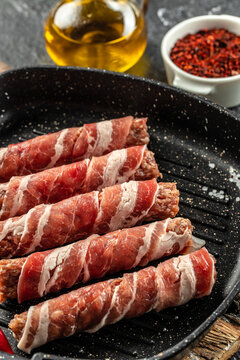 Pork wrapped in bacon in pan on a dark background. vertical image. top view. place for text