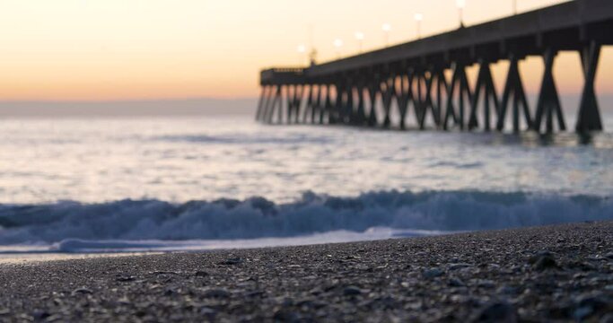 Sunrise at Wrightsville Beach pier, with waves breaking onto the shoreline. 