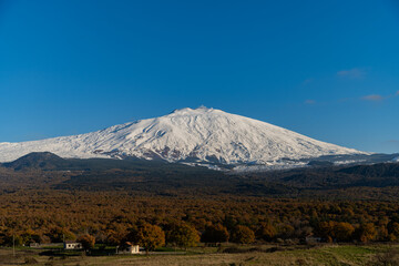 Bronte town under the snowy and majestic volcano Etna and a cloudy blue sky
