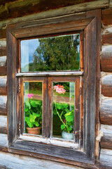 Rustic window with flowers in an old wooden house close-up
