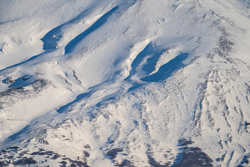 Bronte town under the snowy and majestic volcano Etna and a cloudy blue sky
