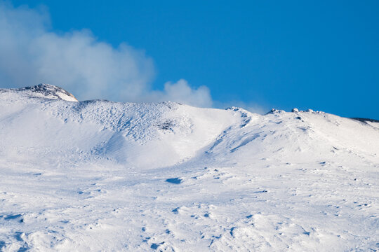 Bronte town under the snowy and majestic volcano Etna and a cloudy blue sky