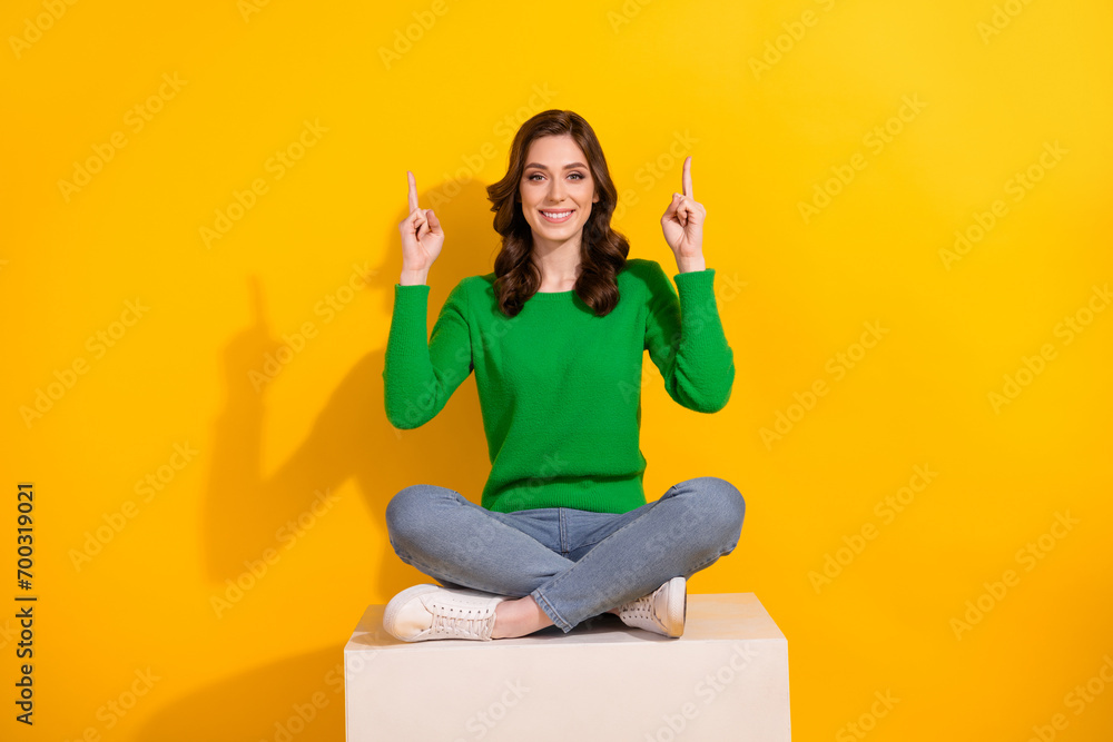 Poster Full length photo of effective promoter girl point fingers above head sit podium introduce up copyspace isolated on yellow color background