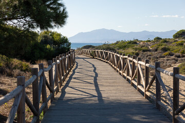 Obraz premium wooden path towards the mediterranean sea with a clear sky