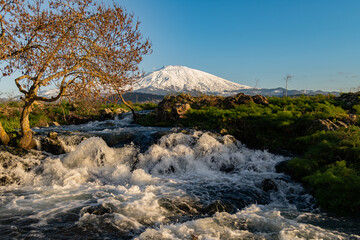 A seasonal river flows under the massive snowcovered Etna volcano. Favare Santa Venera 