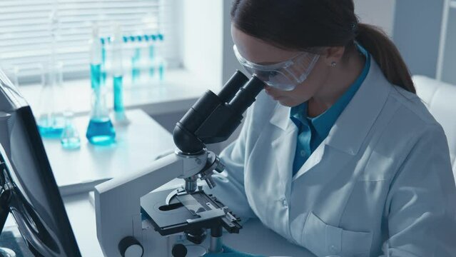 Doctor in medical laboratory directs important investigations. Its sophisticated scientific methods under microscope and the abundance data on computer combine to create new breakthroughs in treatment
