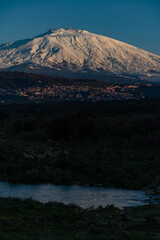 Bronte town under the snowy and majestic volcano Etna and a cloudy blue sky