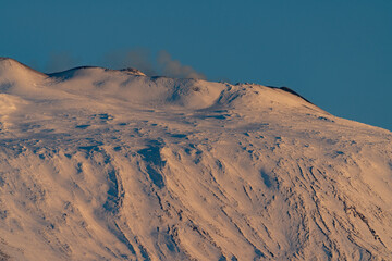 Bronte town under the snowy and majestic volcano Etna and a cloudy blue sky